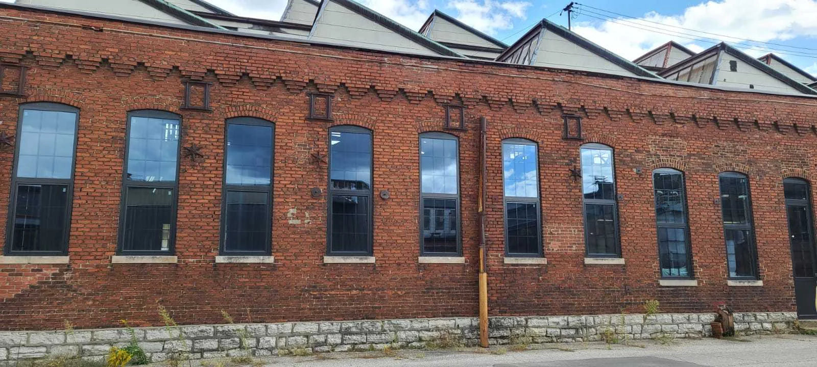 A long brick building with tall dark-framed windows and a sawtooth roofline.